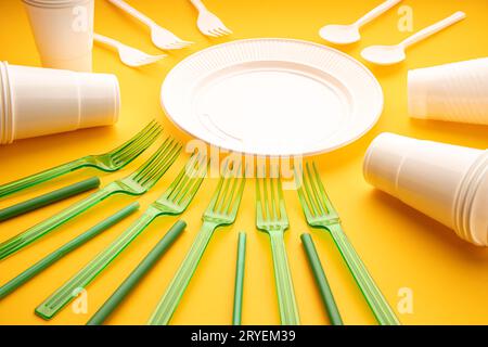 Group of empty plates, cups, forks and utensils on yellow table Stock Photo