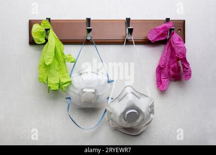 Gloves and respirator masks hanging on clothes rack Stock Photo