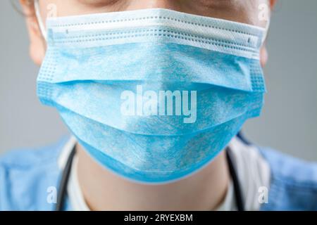 Caucasian doctor or nurse wearing blue protective surgical face mask Stock Photo