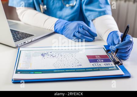 Doctor wearing protective gloves working on laptop computer Stock Photo