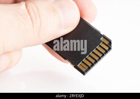 Hand holding a SD memory card on white background. Copy space Stock Photo