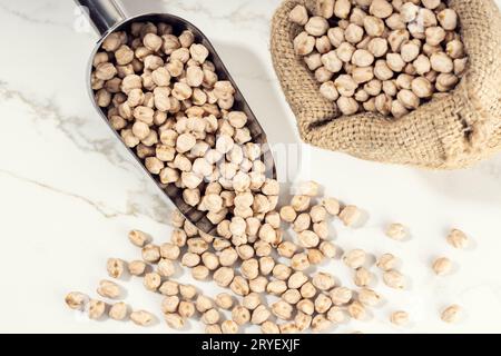 Top view of uncooked Chickpeas on scoop on White marble Background. Cicer arietinum Stock Photo