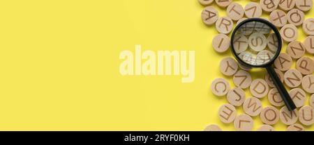 Concept of learning english, searching for word, and information. English alphabet letter and magnifying glass. Yellow background with copy space. Stock Photo