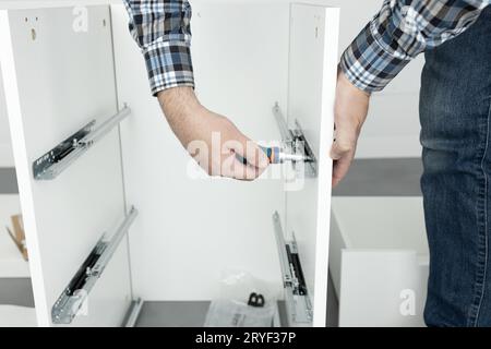 Close up of a Man Assembling a drawer slider Furniture using a screwdriver Stock Photo