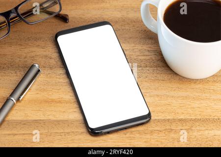 Smartphone mockup template with coffee cup and eyeglasses on wooden table. White screen Stock Photo