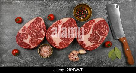 Close up three raw beef ribeye steaks on table Stock Photo