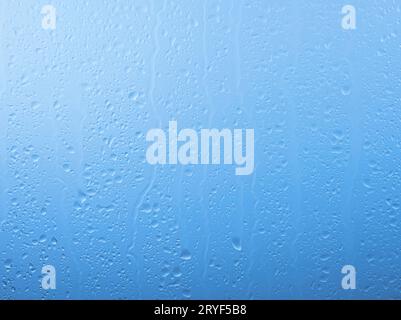 Raindrops on glass window over grey and blue sky Stock Photo