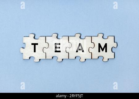 Team word on wooden puzzle pieces isolated on blue background. Top view Stock Photo