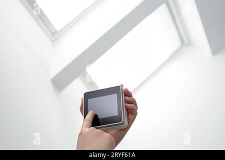 Hand operating a Remote control of a roof windows on indoor. Copy space Stock Photo