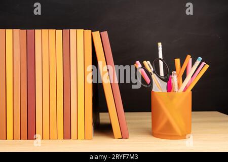 Group of books and pencils on wooden table and blackboard at background. Copy space Stock Photo