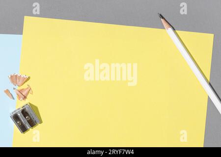 Blank yellow sheet paper, white pencil and sharpener on gray Background. Creative Mock up template flat lay desk Stock Photo
