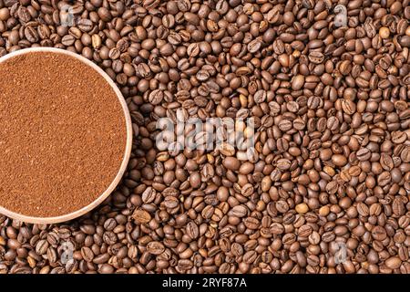 Ground coffee in wooden plate on coffee beans background. Top view. Copy space Stock Photo