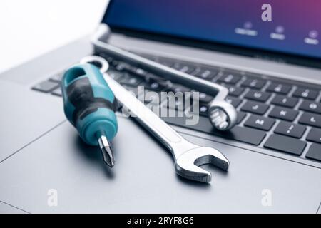 Computer fixing, service or maintenance concept background. Working tools on modern laptop computer Stock Photo