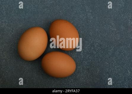 Three brown chicken eggs on dark table Stock Photo