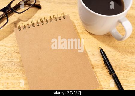 Blank Cardboard notepad on wooden desk with cup of coffee and eyeglasses. Template mock up Stock Photo