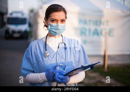 Female emergency services doctor in front of ambulance clinic Stock Photo