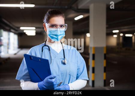 Portrait of young female emergency medical services worker on a parking lot wearing blue protective Stock Photo