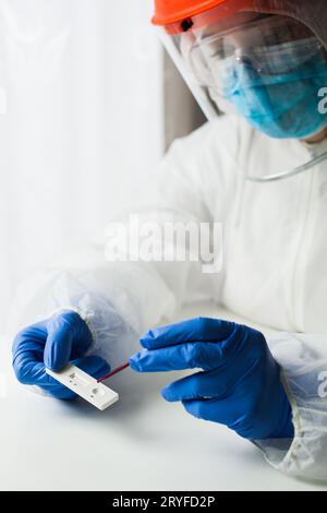 Medical worker performing serology testing in laboratory wearing protective equipment Stock Photo