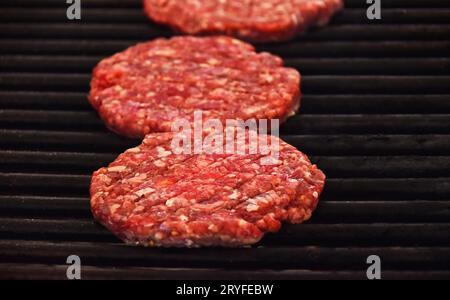 Raw beef burgers for hamburger on barbecue grill Stock Photo