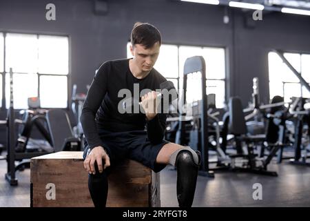 brunette hardworking guy concentrated on working out while sitting on wooden fitness box. close up photo. hobby, challenge, copy space Stock Photo