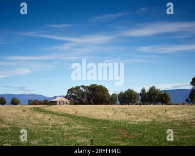 Rural abandoned typical Australian property. Huge blue skies with wispy clouds and parched dry paddock in the foreground. Stock Photo
