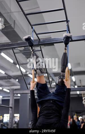 strong man hanging upside down holding rings with hands balancing body, cropped shot focus on artificial legs. willpower Stock Photo