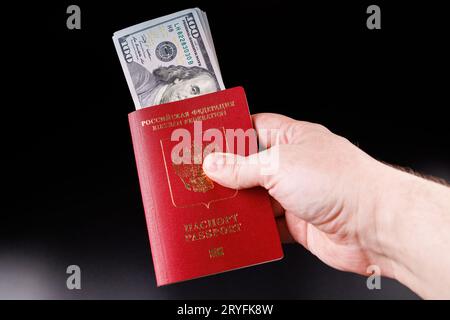 Caucasian hand holding russian international passport with inserted US dollars Stock Photo