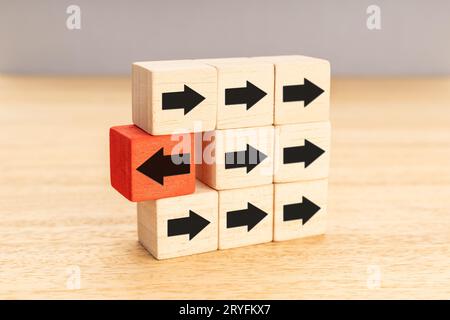 Think different, unique or independent concept. Arrow pointing the opposite way disruptive from other arrows on wooden blocks Stock Photo