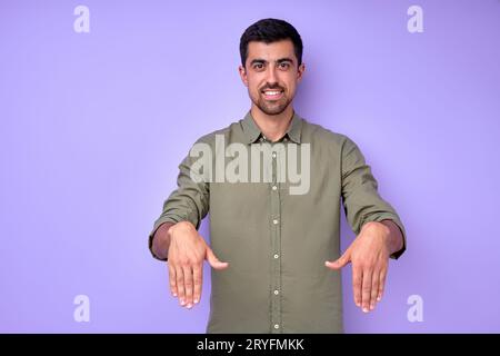 Young cheerful happy deaf mute man saying the word son using sign language on blue background Stock Photo