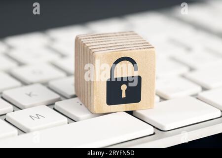 Computer security risk concept. Open padlock icon on wooden cube on computer keyboard Stock Photo
