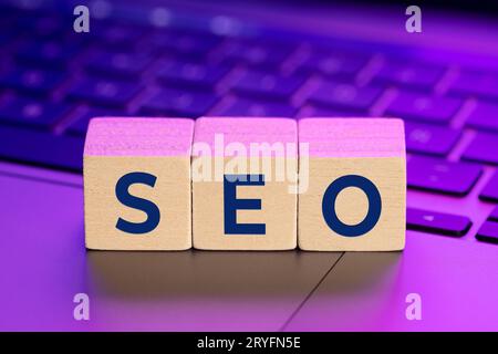 SEO word on wooden blocks on laptop with colorful lights. Search Engine optimization concept Stock Photo