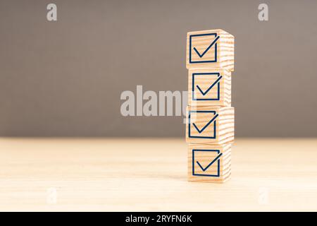Checking or checklist concept. Wooden block with check icon stacked on wooden table. Copy space Stock Photo