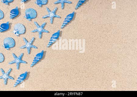 Summer background with blue seashell pattern on beach sand background. Copy space. Top view Stock Photo