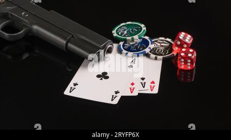 Angle shot of a weapon next to some playing cards and dice on a black reflecting surface. Stock Photo