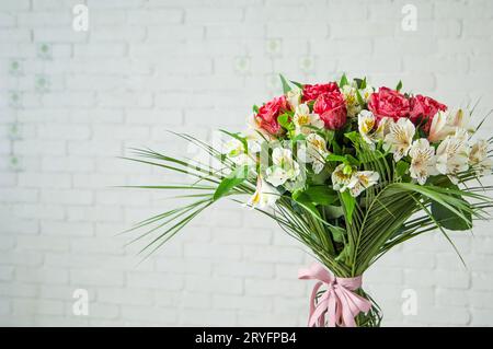 Beautiful bouquet with roses and white alstroemeria against a white wall Stock Photo