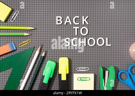 Back to school background. White phrase made of plastic letters and Variety of Office and school supplies on gray background Stock Photo