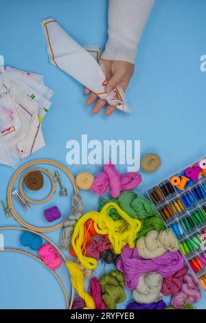 Cheerful young woman embroiderer likes to embroider at home. Woman is engaged in embroidering. Womens hands are embroidering. Stock Photo