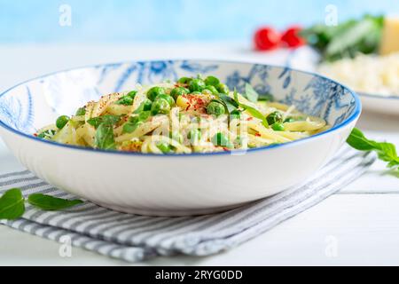 Spaghetti with zucchini and green peas close up. Stock Photo