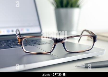 Close up of Eyeglasses on modern laptop on desk. Eye health and vision using computer and modern screen devices Stock Photo