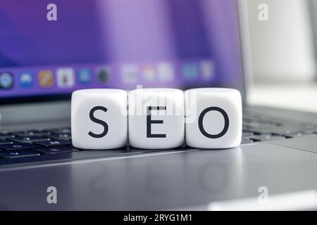 SEO or Search Engine optimization concept. Cube blocks with text on modern laptop Stock Photo
