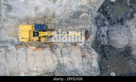 Yellow tracked bulldozer performs earthworks - aerial view shot. Yellow tracked tractor rakes the ground to build an asphalt roa Stock Photo