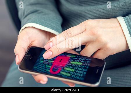 Mobile phone in female hands with screen showing compromised virus infected device. Cyber attack. Stock Photo