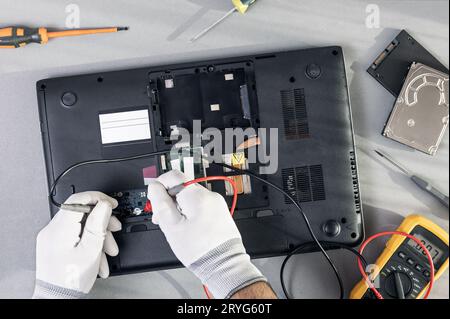 Technician hands repairing a laptop computer. Top view Stock Photo