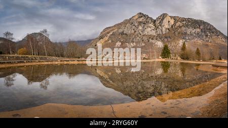 Mountain peak and trees reflecting in artificial pond, Pyrenees Mountains, France Stock Photo