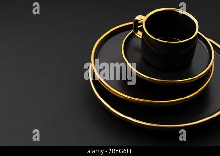 A set of black and golden ceramic plates and cup on a black background Stock Photo
