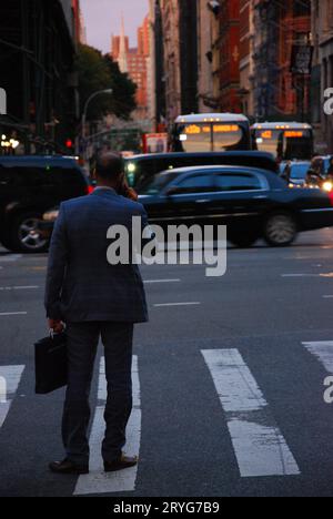 Back shot of businessman in New York in suit talking on cell phone on the streets of New York City, US Stock Photo