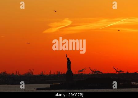 Silhouette of Statue of Liberty and Liberty Island in New York against ...