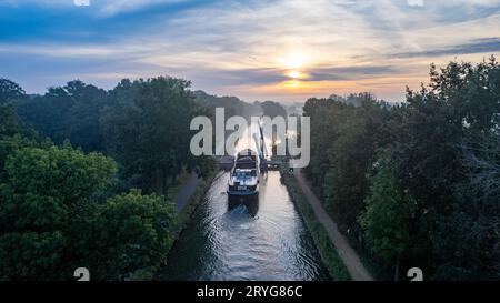Aerial view of a colourful dramatic sunrise sky over a canal with a cargo boat in Belgium. Canals with water for transport, agri Stock Photo