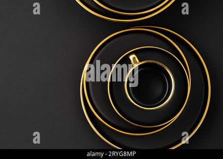 A set of black and golden ceramic plates and cup on a black background. Top view Stock Photo