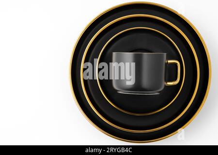 A set of black and golden ceramic plates and cup on a white background. Top view Stock Photo